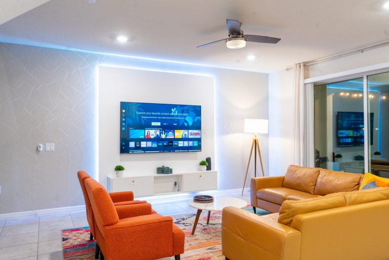 Modern living room with a brown leather sofa, vibrant rug, and open kitchen area.