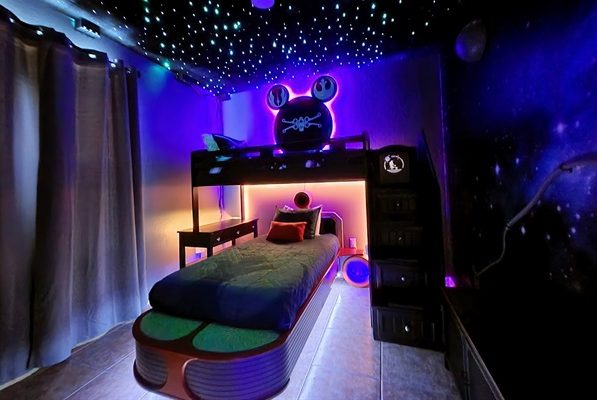 A futuristic bedroom with glowing stars, a loft bed, and colourful decorations.