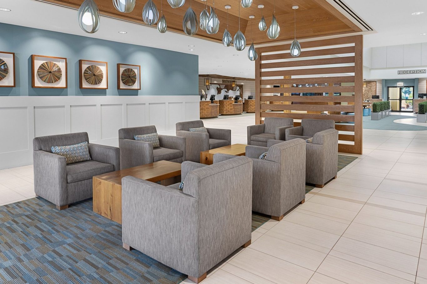 Modern lounge area with grey chairs, wooden accents, and framed artwork on the walls.