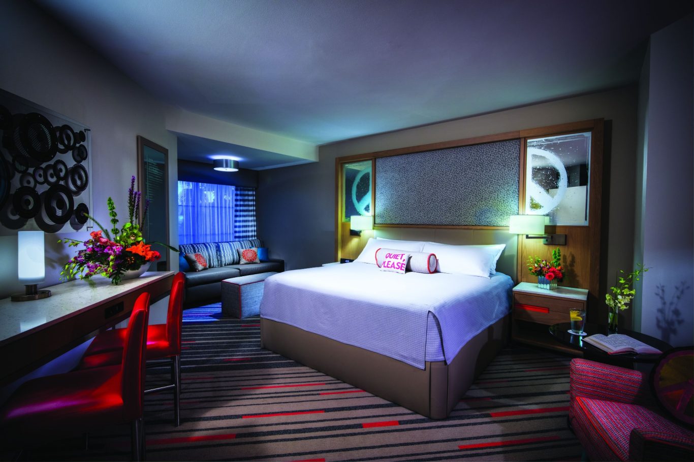 Modern hotel room with a large bed, stylish decor, and vibrant lighting.