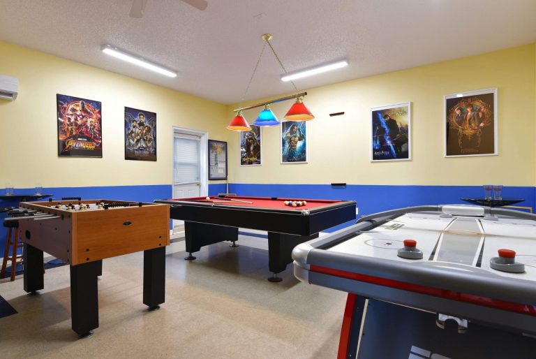 Game room featuring a pool table, foosball table, and air hockey table against yellow walls.