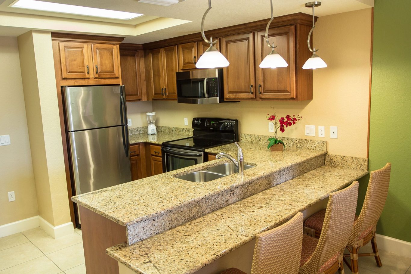 Modern kitchen with wooden cabinetry, granite countertops, and stainless steel appliances.