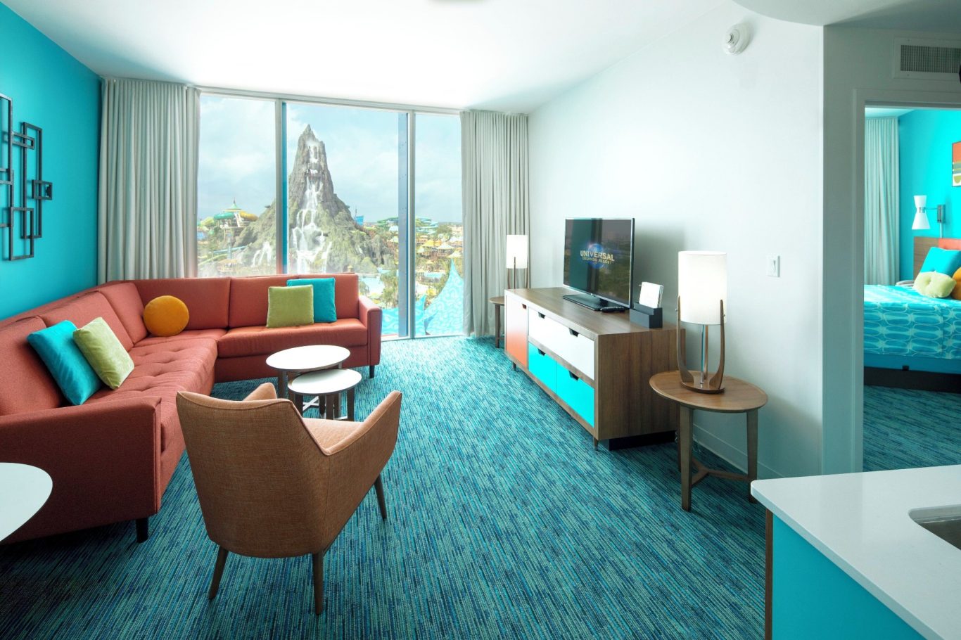 Modern hotel suite featuring a turquoise theme, seating area, and city view.