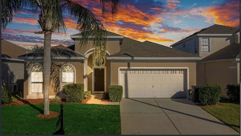 A modern house with a garage, lush garden, and a vibrant sunset sky in the background.