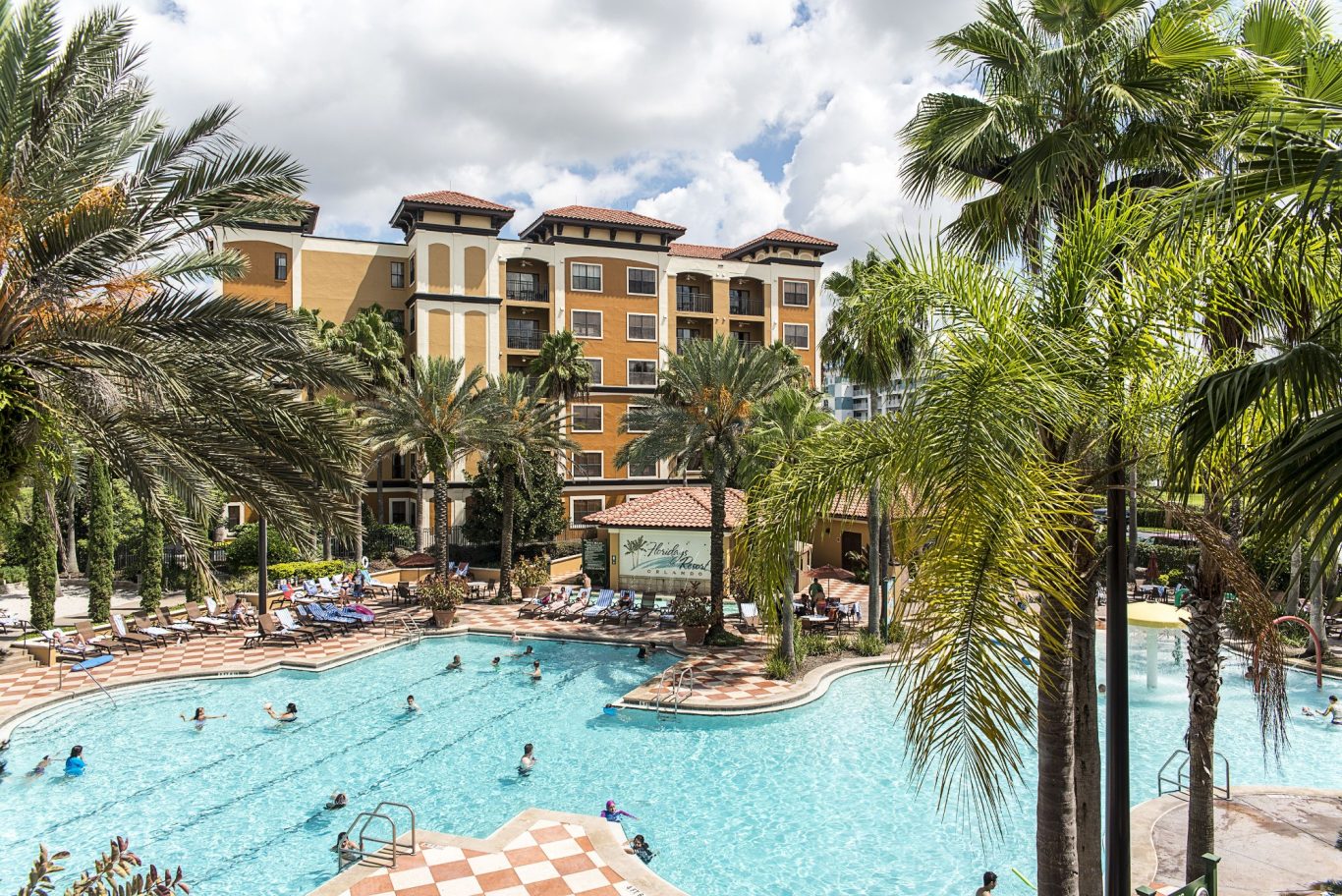 A tropical pool scene with palm trees and a hotel, featuring people swimming and relaxing.