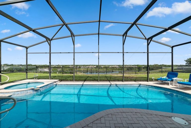 Bright pool area with a screened enclosure, overlooking a scenic green landscape.