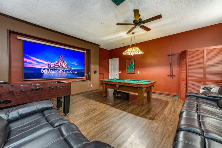 A cozy game room featuring a pool table, large screen, and comfortable seating.