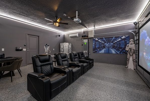 Home theatre with black recliners, projector, and futuristic decor.