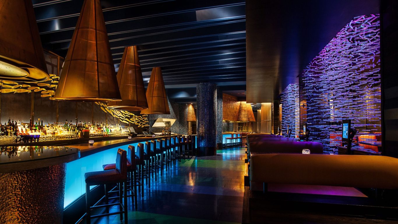 Stylish bar interior with vibrant lighting and modern decor, featuring sculptural elements.