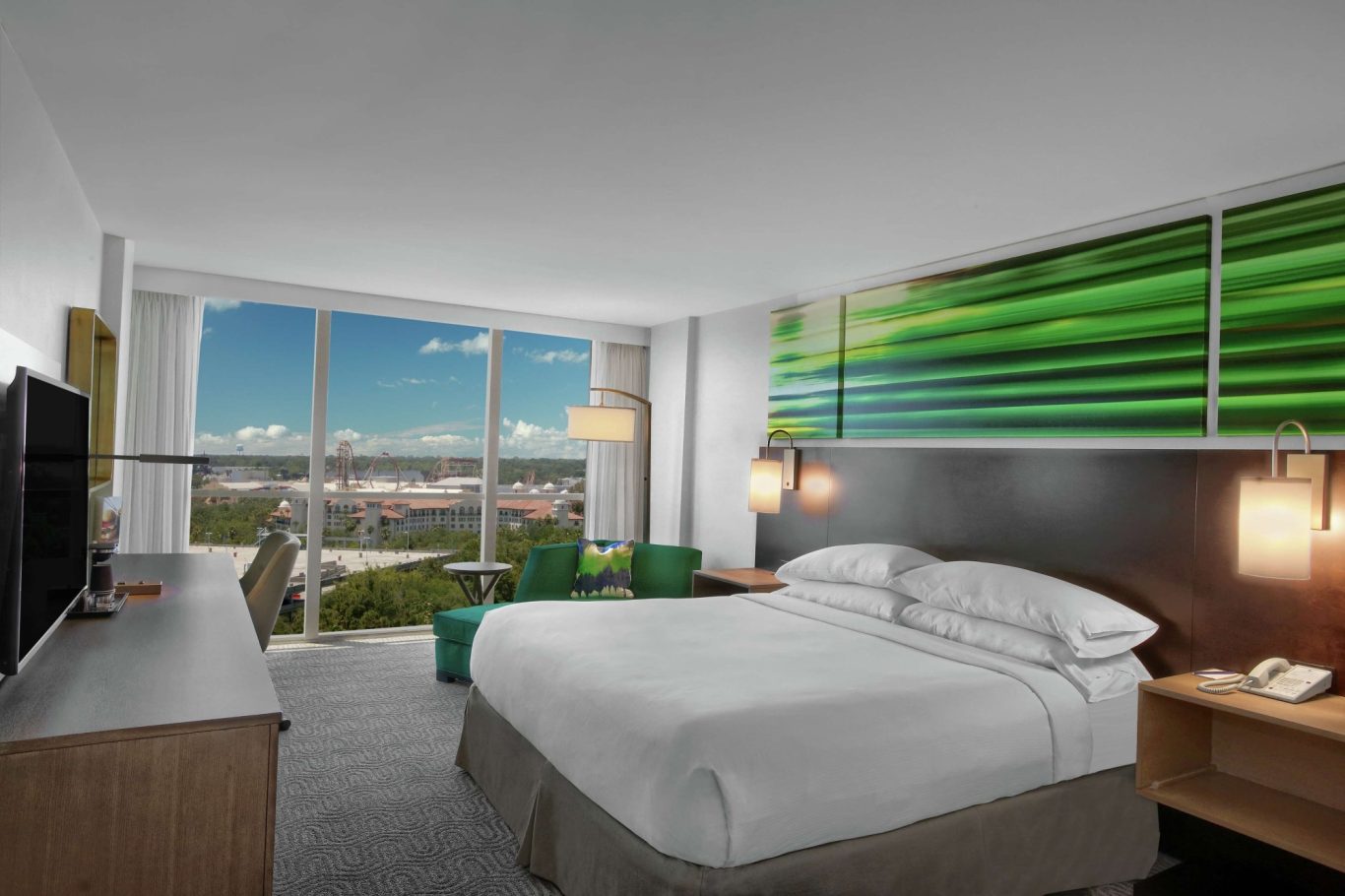 Modern hotel room with a king-sized bed, large windows, and a city view.