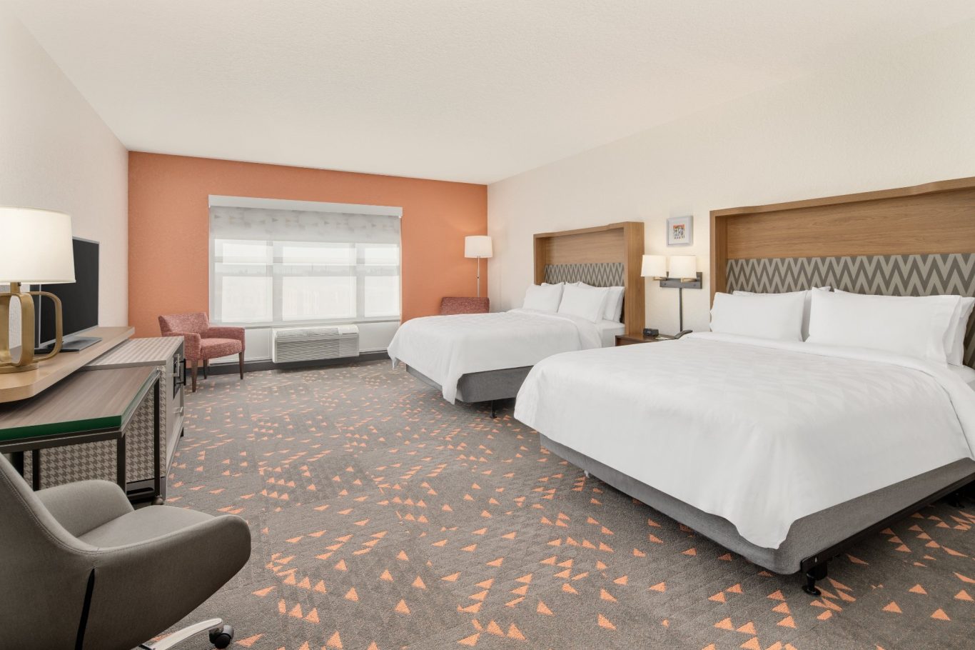 Hotel room with two beds, a desk, and large windows, featuring a modern decor.