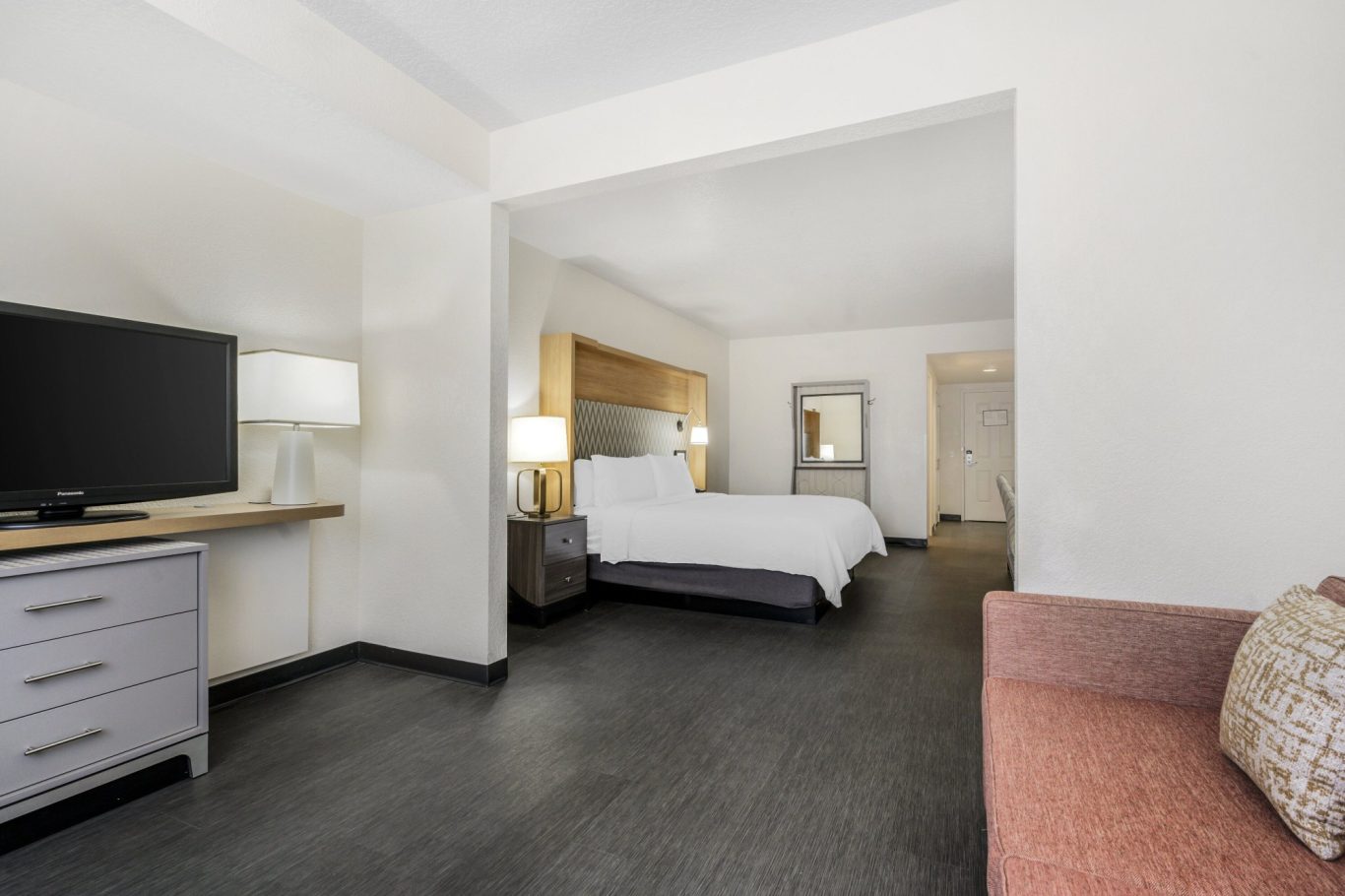 Modern hotel room featuring a large bed, TV, and seating area.