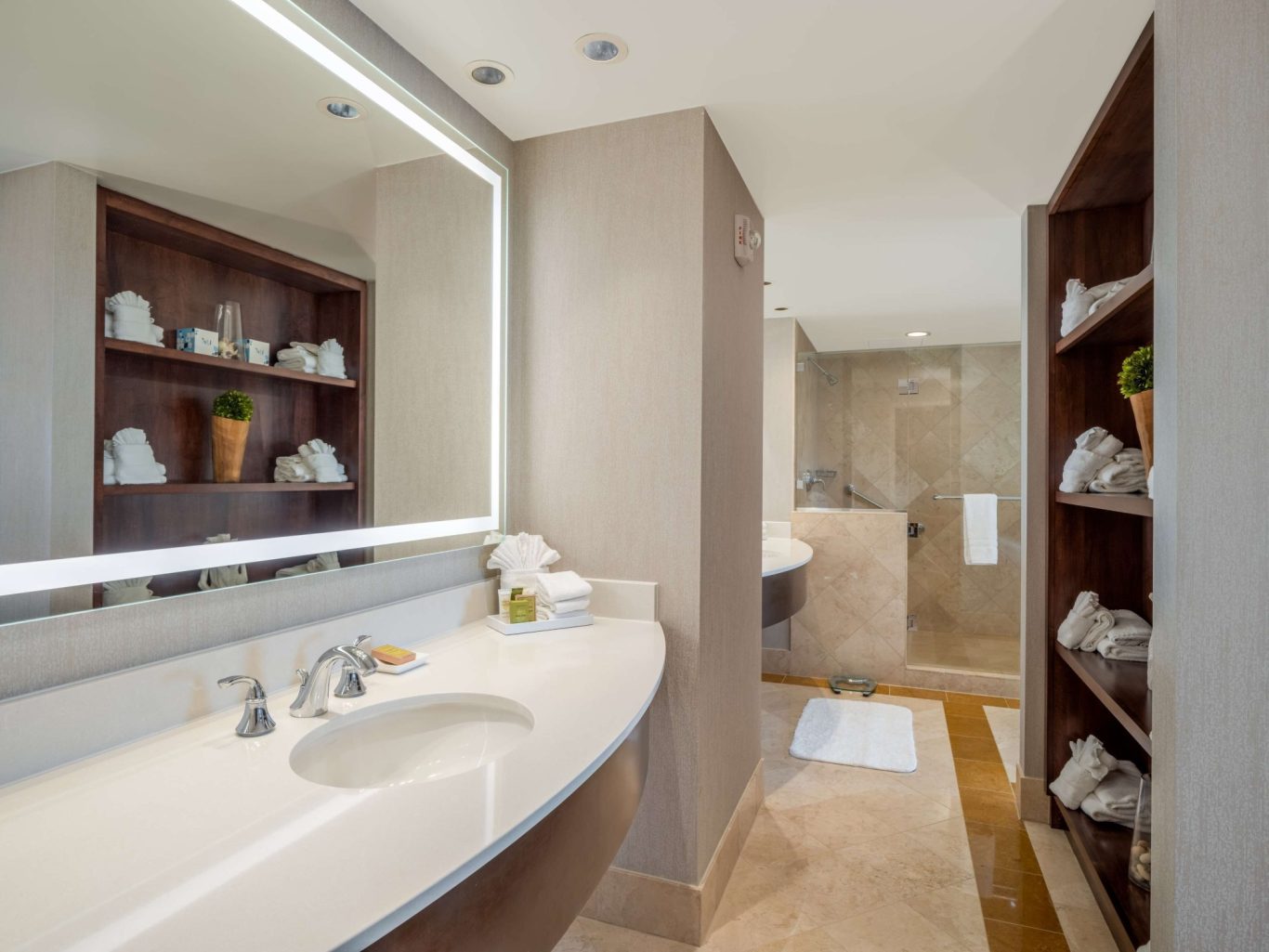Modern bathroom with a sleek sink, large mirror, and neatly organized towels on shelves.
