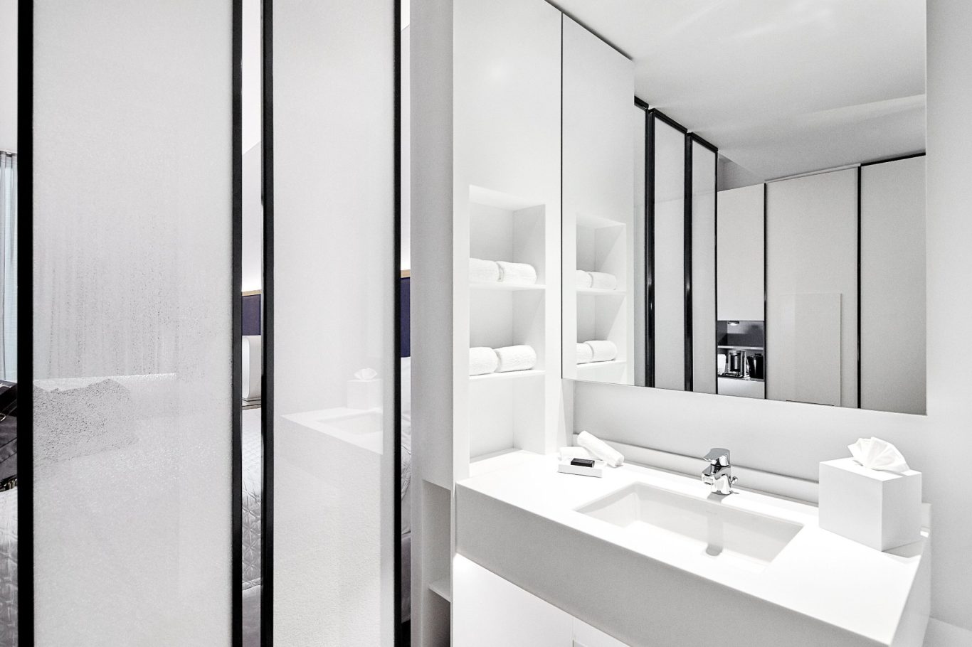 Modern bathroom with a sleek white sink and glass partitions.