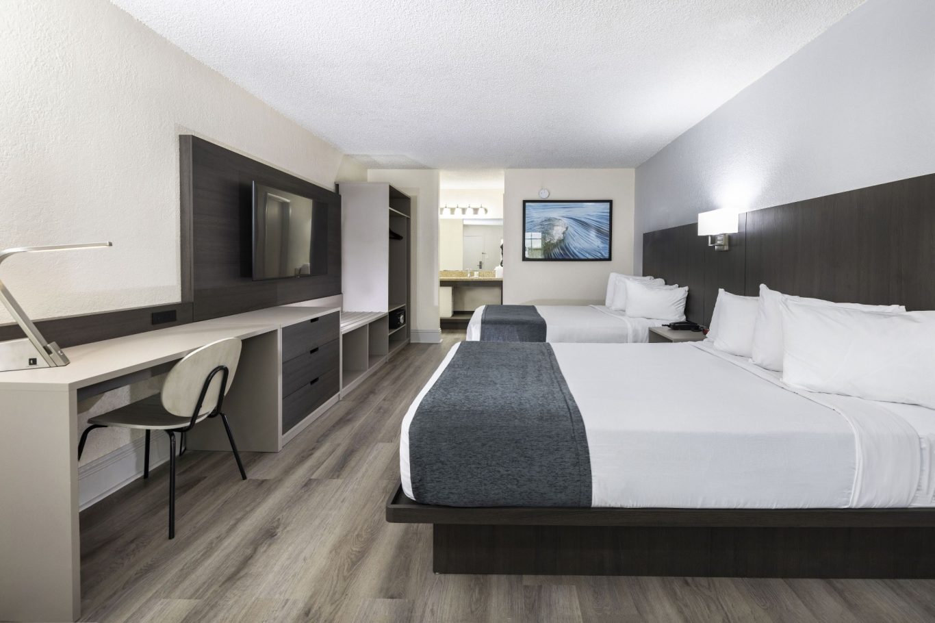 Modern hotel room with two beds, desk, television, and en-suite bathroom.