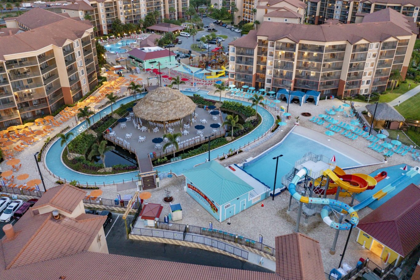 Resort pool area with slides, surrounded by landscaped grounds and buildings.