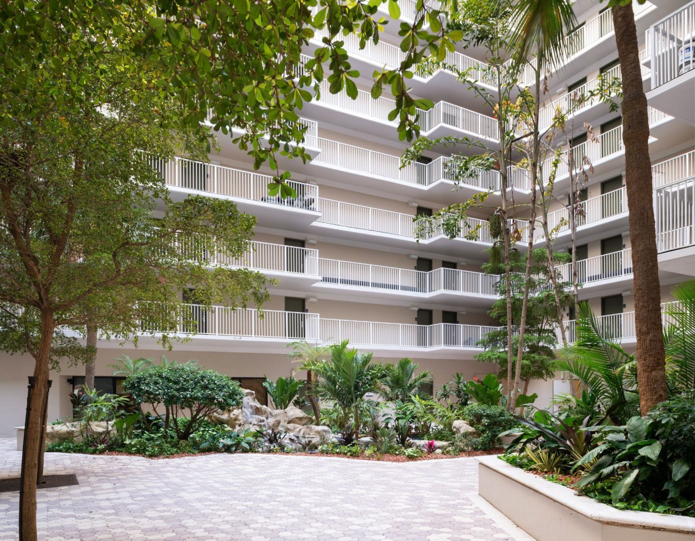 A modern courtyard surrounded by buildings and lush greenery.