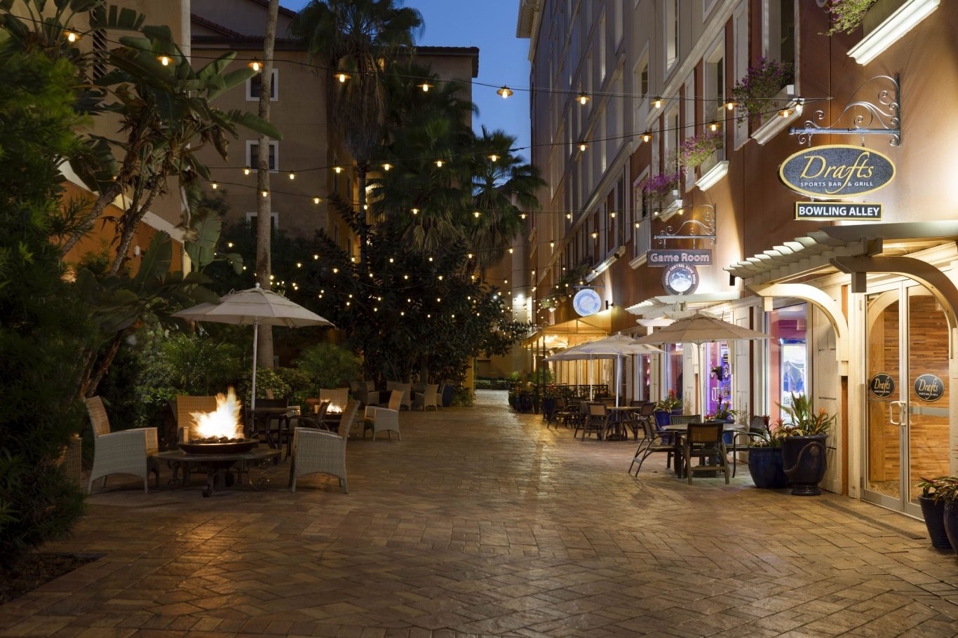 A charming, dimly lit cobblestone street with decorative lights and outdoor seating.