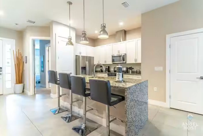 Modern kitchen featuring bar seating, stainless steel appliances, and light-coloured cabinetry.