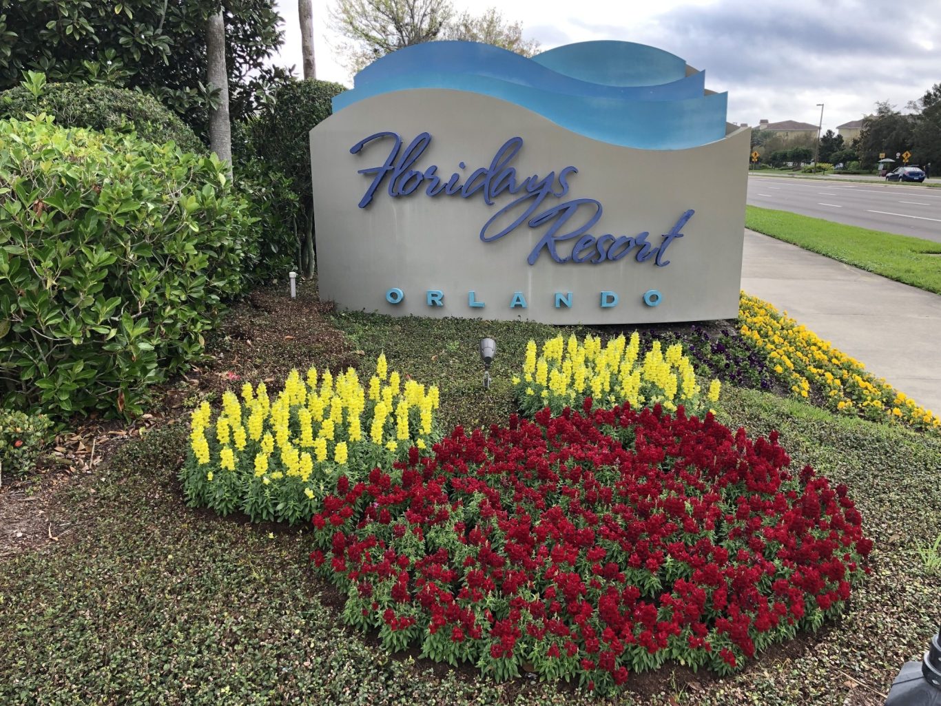 Sign for Holiday Board with colourful flower beds in front.