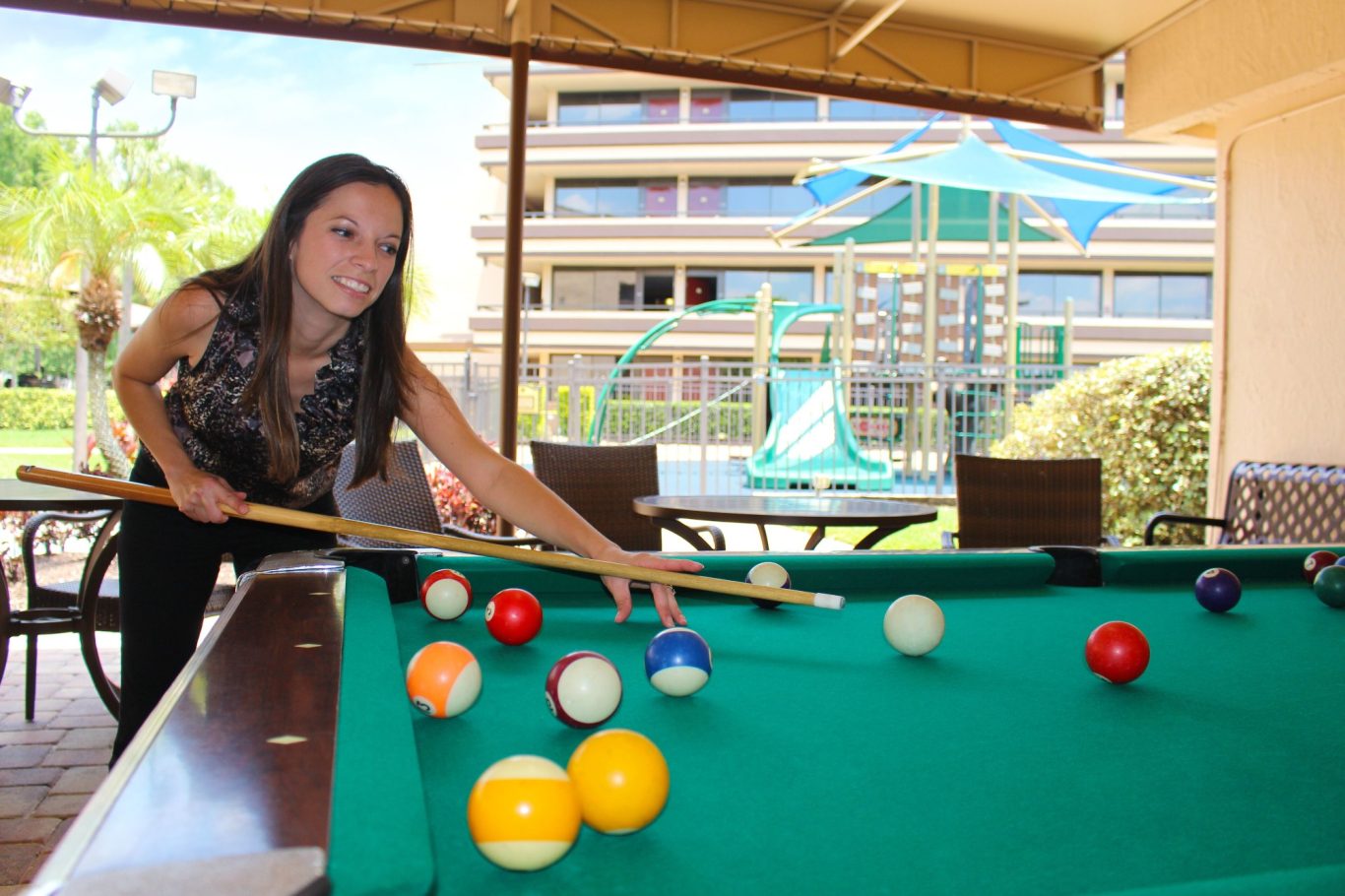 A woman playing billiards in a sunny indoor setting.