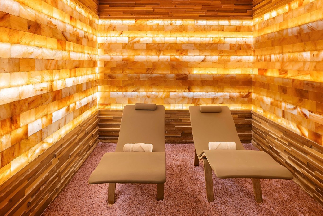 Relaxation area with two lounge chairs surrounded by warm, glowing salt brick walls.