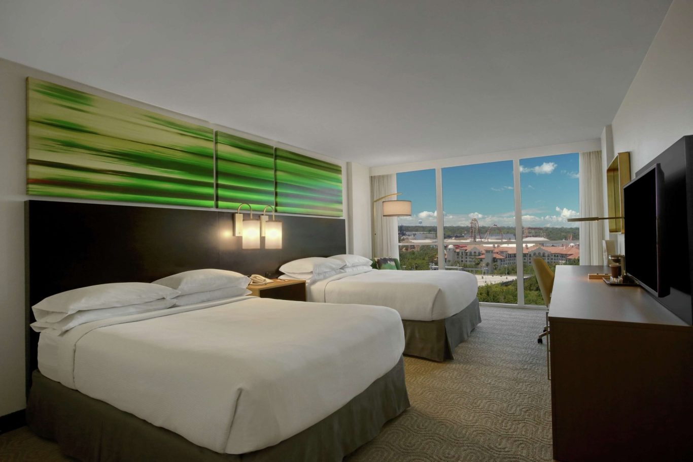 Modern hotel room with two beds and a large window offering a city view.